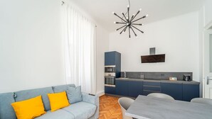 Una sala de estar moderna con un sofá, una mesa de comedor y una cocina con armarios y electrodomésticos.