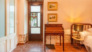 Une pièce avec une porte en bois, une petite table sur laquelle se trouve une lampe, et deux tableaux encadrés accrochés au mur.