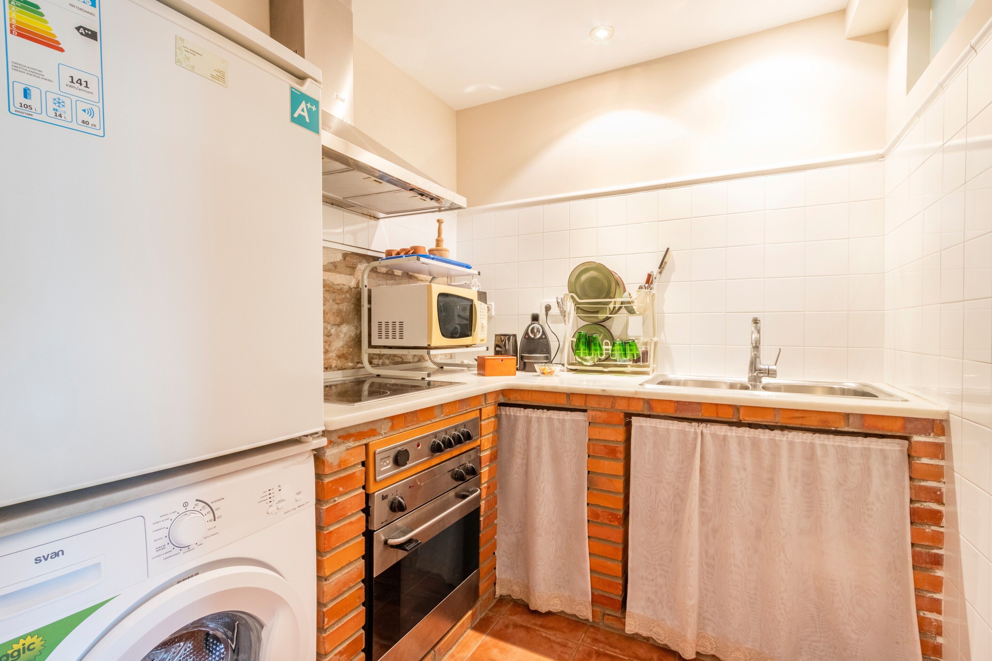 Uma cozinha compacta com máquina de lavar, forno, micro-ondas e pia.