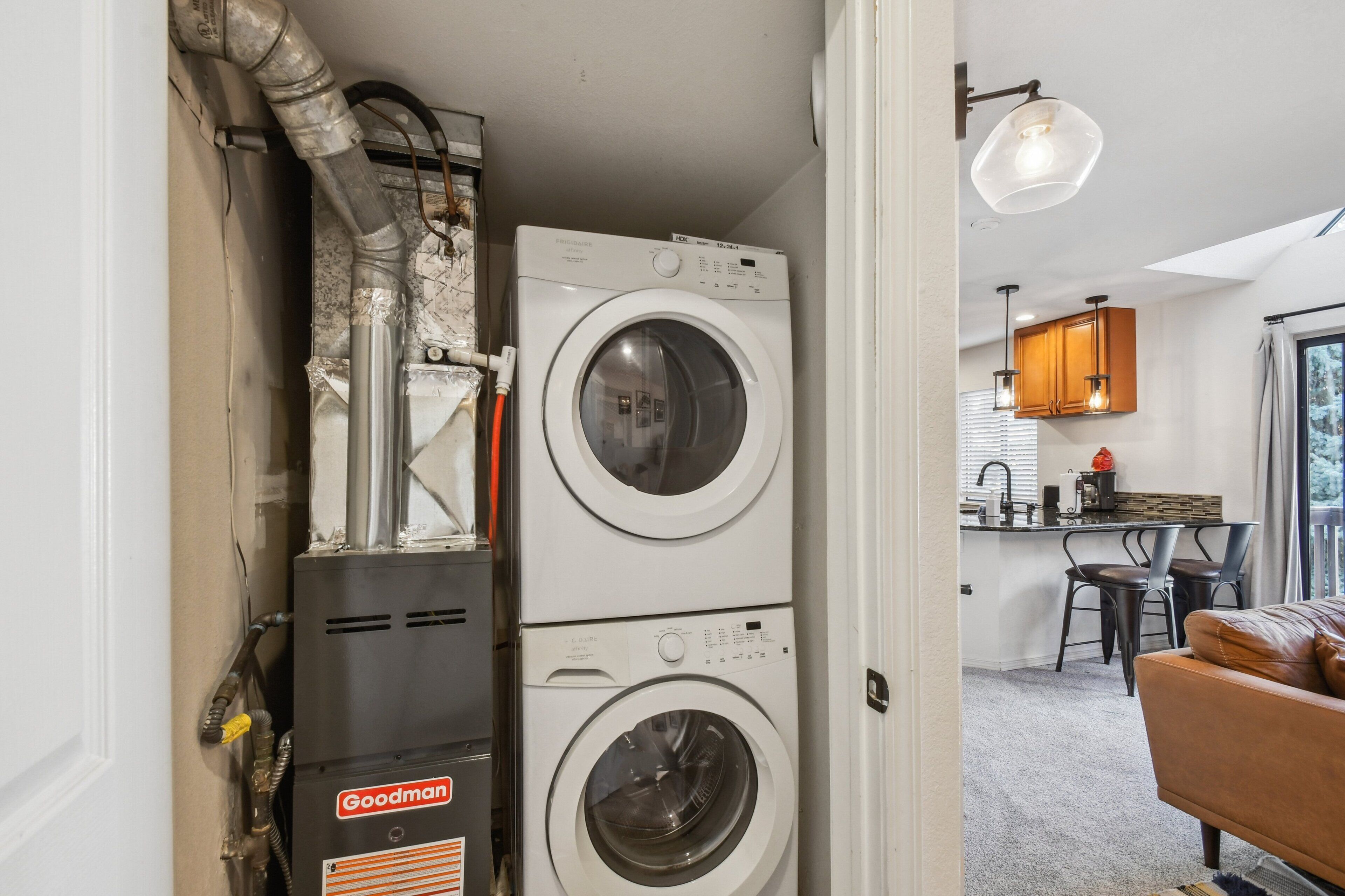 A laundry area with stacked washing machines and a Goodman heater.