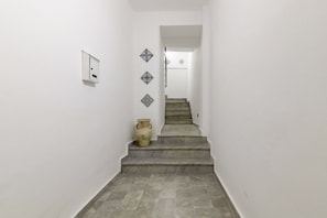 A staircase with a white wall, a light switch, and decorative tiles.
