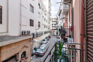 Eine schmale Stadtstraße mit parkenden Autos, Gebäuden mit Balkonen und einem sichtbaren Hydranten.
