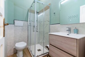 A bathroom with a glass-enclosed shower, a white toilet, a wooden vanity with a sink, and a mirror. - GuestHost - Cozy 61sqm apartment, for 4 people, on the 1st floor of a renovated building (NO lift and with stairs to access it). The property is located in a central area (Traffic Restricted Area), in the historic center of Palermo, a few minutes on foot (Palermo)