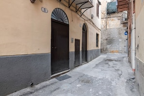 A narrow alleyway with a building featuring arched doorways and a number '3' sign.