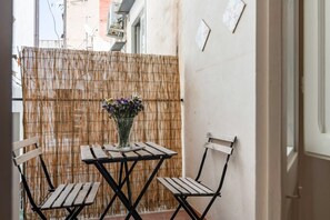 A small outdoor seating area with a table and two chairs, a bamboo screen, and a vase with flowers. - GuestHost - Cozy 61sqm apartment, for 4 people, on the 1st floor of a renovated building (NO lift and with stairs to access it). The property is located in a central area (Traffic Restricted Area), in the historic center of Palermo, a few minutes on foot (Palermo)
