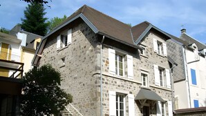 A stone building with a staircase leading to the entrance, a grill outside, and a small garden area. - Villa 'L'autre Vie Là' with Mountain Views, Private Terrace and Wi-Fi (La Bourboule)