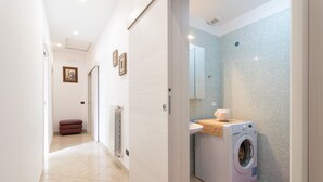 A hallway leading to a bathroom with a washing machine, a sink, and a tiled shower wall. - Apartment 'Casa Luxury' with Shared Terrace, Wi-Fi and Air Conditioning (Santeramo In Colle)
