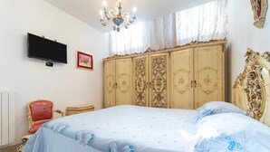 A bedroom with a bed, a television, a red chair, a wardrobe, and a chandelier. - Apartment 'Casa Luxury' with Shared Terrace, Wi-Fi and Air Conditioning (Santeramo In Colle)
