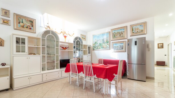 A dining area with a table set for four, surrounded by white chairs, a red tablecloth, and a modern refrigerator. - Apartment 'Casa Luxury' with Shared Terrace, Wi-Fi and Air Conditioning (Santeramo In Colle)