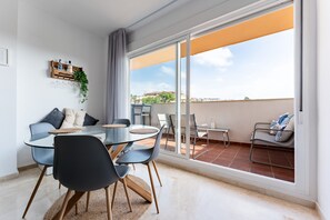 Un soggiorno moderno con tavolo in vetro, sedie, divano e un balcone con vista.