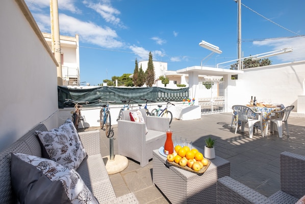 A patio area with wicker furniture, a table with chairs, and a fruit basket.