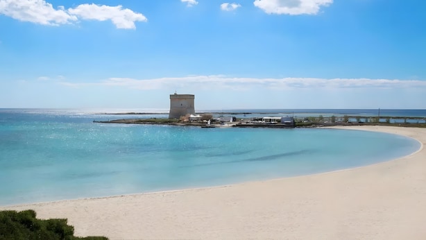 A beach with a tower, clear blue sky, and calm sea. - Holiday Home 'Villa Heart Island Sea View' with Sea View, Wi-Fi and Air Conditioning (Torre Squillace)