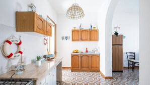 A kitchen with wooden cabinets, a gas stove, a hanging life preserver, and a patterned floor. - Holiday Home 'Villa Heart Island Sea View' with Sea View, Wi-Fi and Air Conditioning (Torre Squillace)