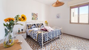 A bedroom with a bed, a bedside table, a vase with flowers, and a window. - Holiday Home 'Villa Heart Island Sea View' with Sea View, Wi-Fi and Air Conditioning (Torre Squillace)