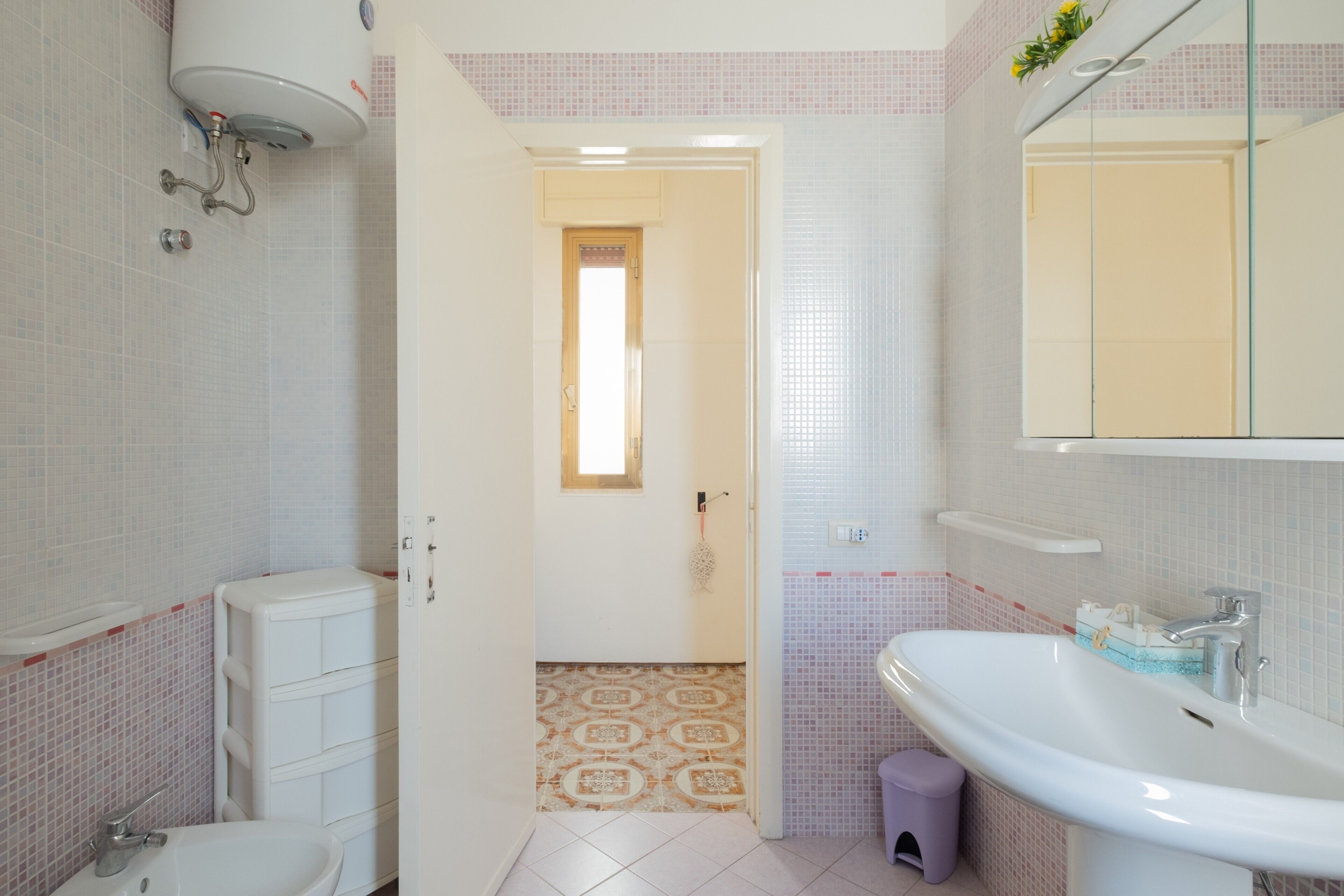 Un baño con inodoro, bidé, lavamanos y espejo.