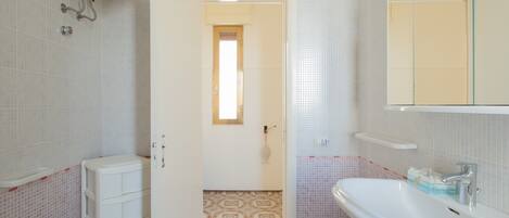 Un baño con inodoro, bidé, lavamanos y espejo.