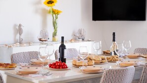 A dining table set with plates, glasses, a bottle of wine, and a vase with sunflowers. - Holiday Home 'Villa Heart Island Sea View' with Sea View, Wi-Fi and Air Conditioning (Torre Squillace)