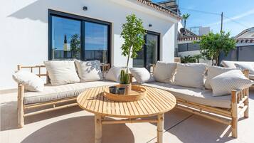 Un espace extérieur aménagé avec un canapé et une table ronde en bois, un pot de fleurs et un cactus.