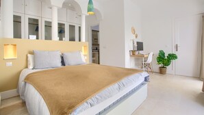Une chambre à coucher avec un lit, un bureau, une chaise et une plante en pot.
