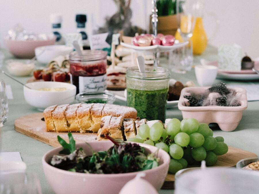 Une table dressée avec divers aliments, notamment une miche de pain, un saladier rempli de salade et une assiette de raisins.