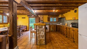 Una cocina rústica con vigas de madera, una isla de piedra y un comedor con mobiliario de madera.