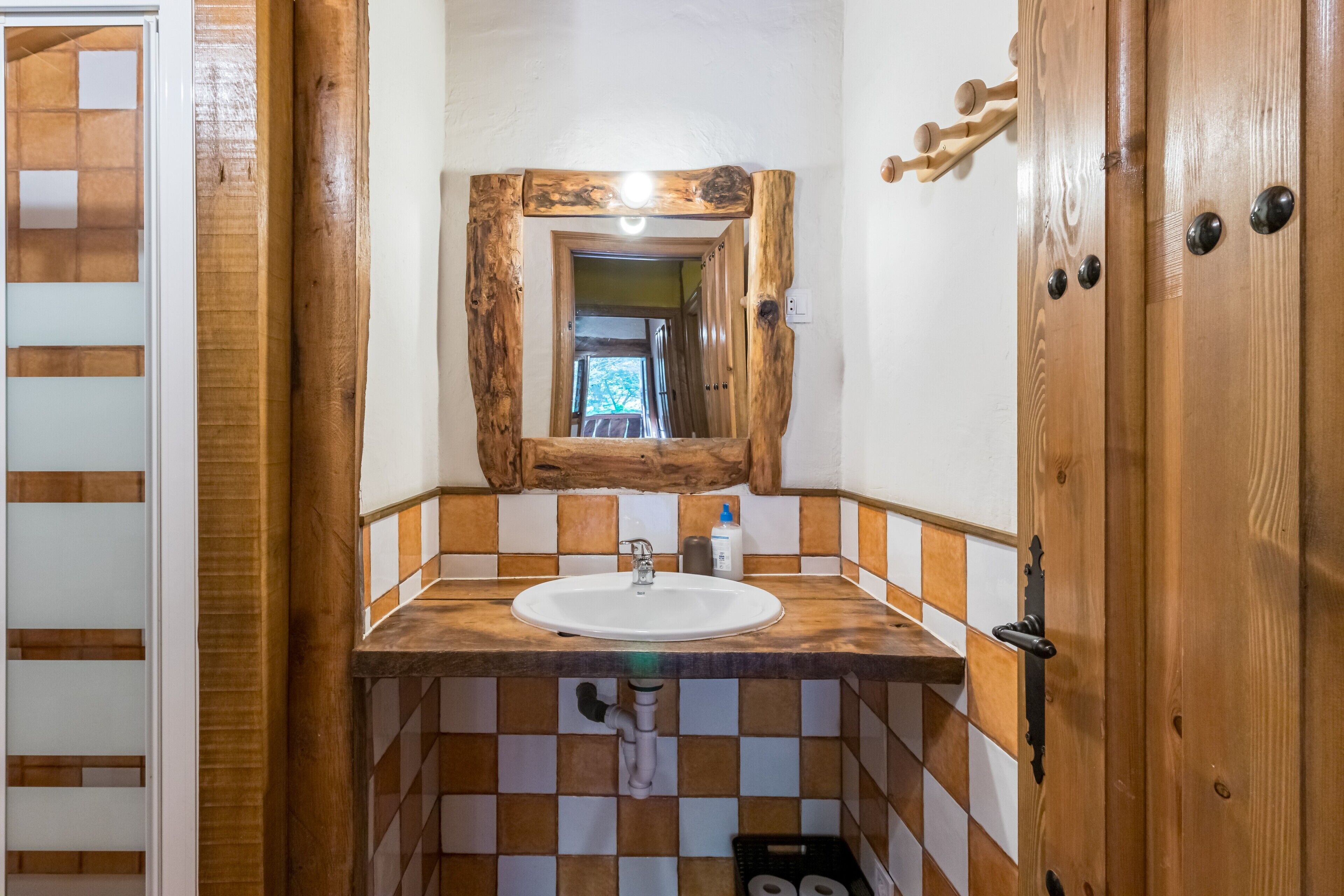 A bathroom with a wooden vanity, a sink, a mirror, and a tiled floor.