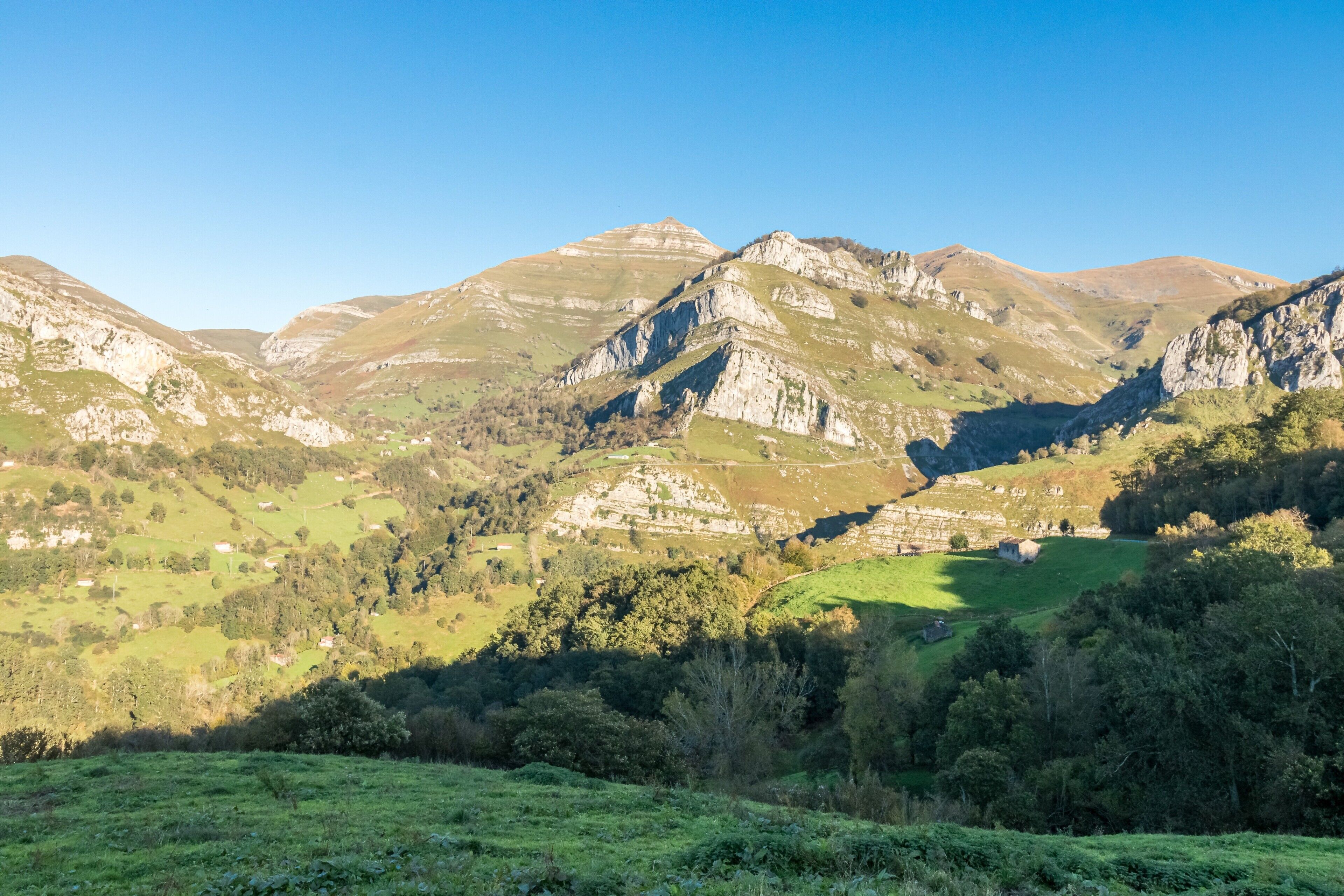 Un paisaje montañoso con valles verdes y afloramientos rocosos.