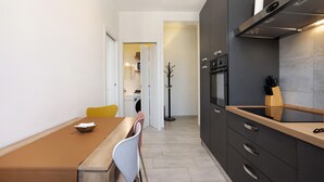 A modern kitchen with a wooden dining table, chairs, and a built-in oven.