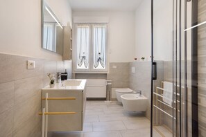 Une salle de bain moderne équipée d’un lavabo, d’un bidet et d’une douche à parois de verre.