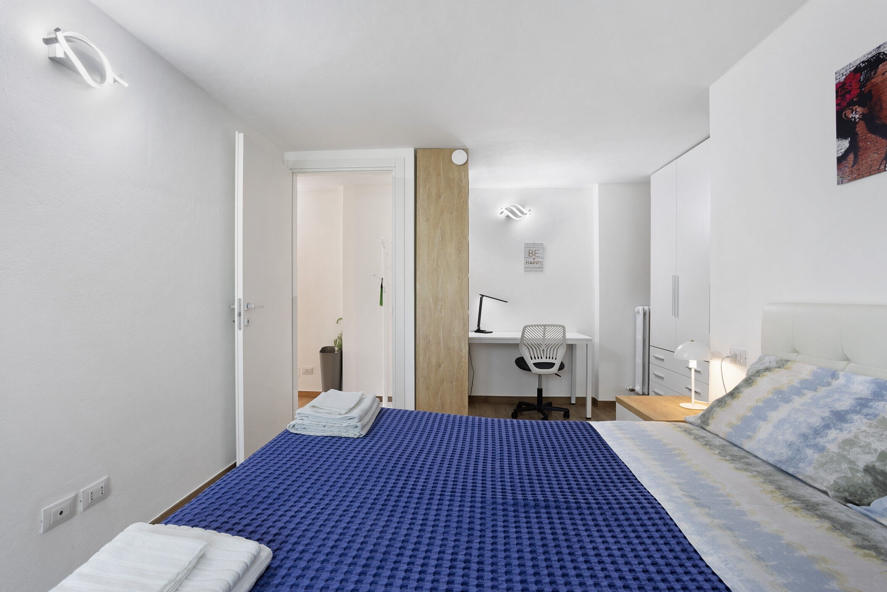 Une chambre à coucher avec un lit, un bureau, une chaise et une table de chevet.