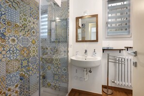 Une salle de bain avec des carreaux décorés, un lavabo, un miroir et un radiateur.