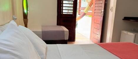 A bedroom with a bed, a bedside table, and a view of the outside.