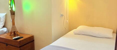 A bedroom with a bed, a nightstand with a lamp, and a wall-mounted light fixture.