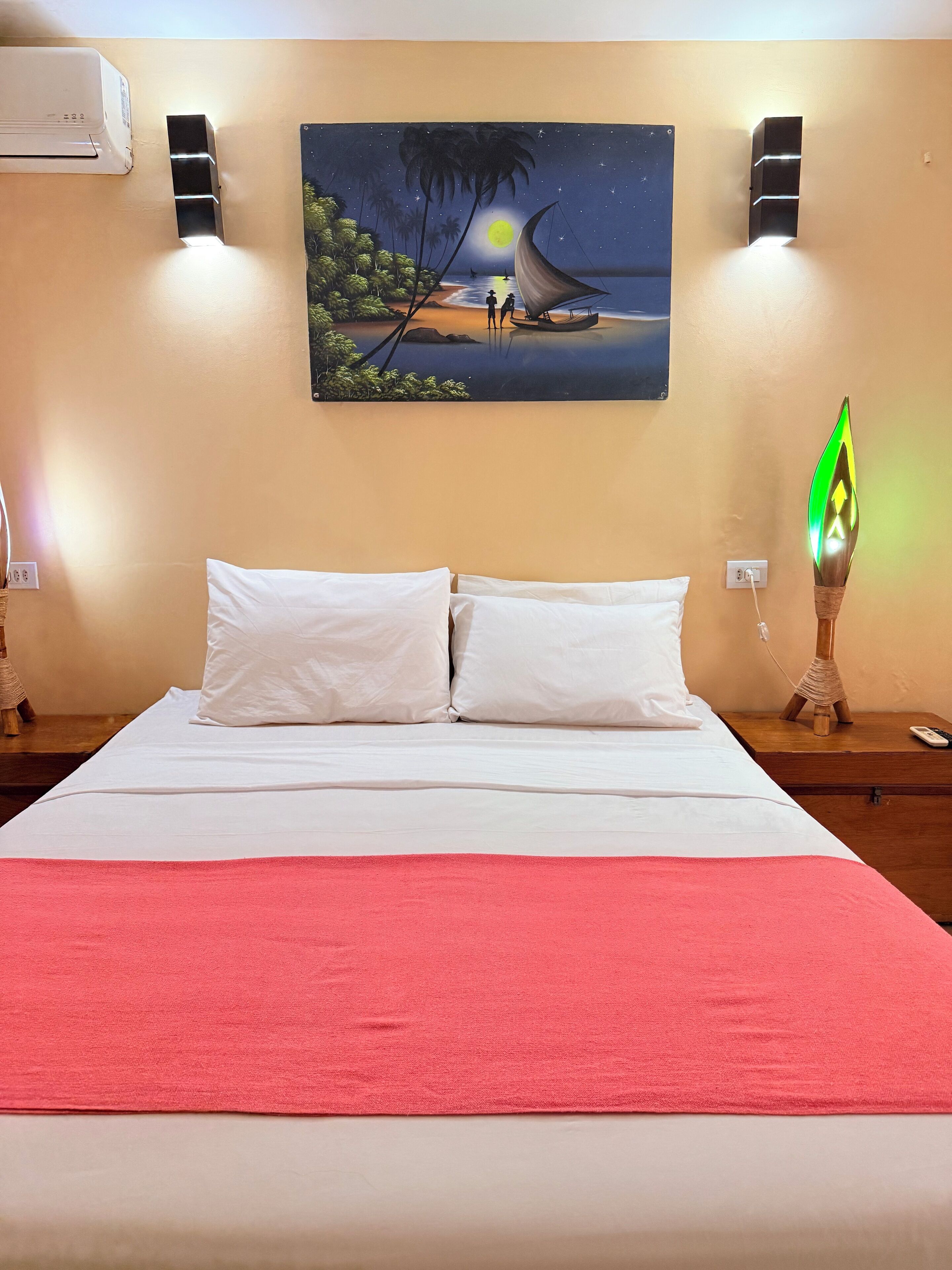 A hotel room with a bed, a night sky painting, wall-mounted speakers, and a nightlight.