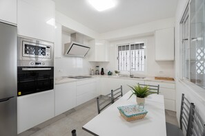 A modern kitchen with white cabinetry, a built-in oven, a microwave, and a window with bars. - Vacation Apartment 'Villa En Las Caletillas' with Sea View, Private Terrace and Wi-Fi (Punta Larga)