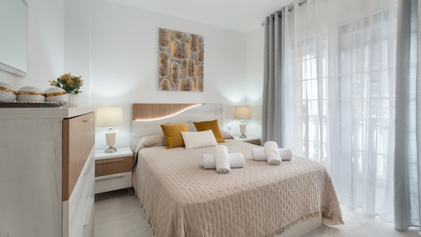 A modern hotel room with a large bed, bedside tables with lamps, a wall-mounted artwork, and sheer curtains. - Vacation Apartment 'Villa En Las Caletillas' with Sea View, Private Terrace and Wi-Fi (Punta Larga)