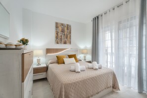 A modern hotel room with a large bed, bedside tables with lamps, a wall-mounted artwork, and sheer curtains. - Vacation Apartment 'Villa En Las Caletillas' with Sea View, Private Terrace and Wi-Fi (Punta Larga)
