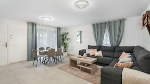 A modern living room with a sofa, coffee table, dining table, chairs, and a potted plant. - Vacation Apartment 'Villa En Las Caletillas' with Sea View, Private Terrace and Wi-Fi (Punta Larga)