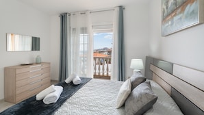 A bedroom with a bed, a dresser, a nightstand, a painting, and a view of a balcony. - Vacation Apartment 'Villa En Las Caletillas' with Sea View, Private Terrace and Wi-Fi (Punta Larga)