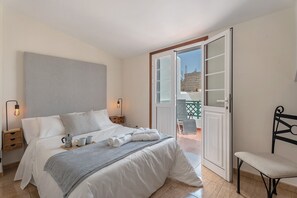 A bedroom with a bed, bedside tables, a chair, a balcony door, and a view of the outside.