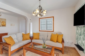 A living room with a sofa set, a coffee table, a chandelier, a television, and a window with shutters. - Vacation Home 'Morgana' with Sea View, Private Terrace and Wi-Fi (Abades)