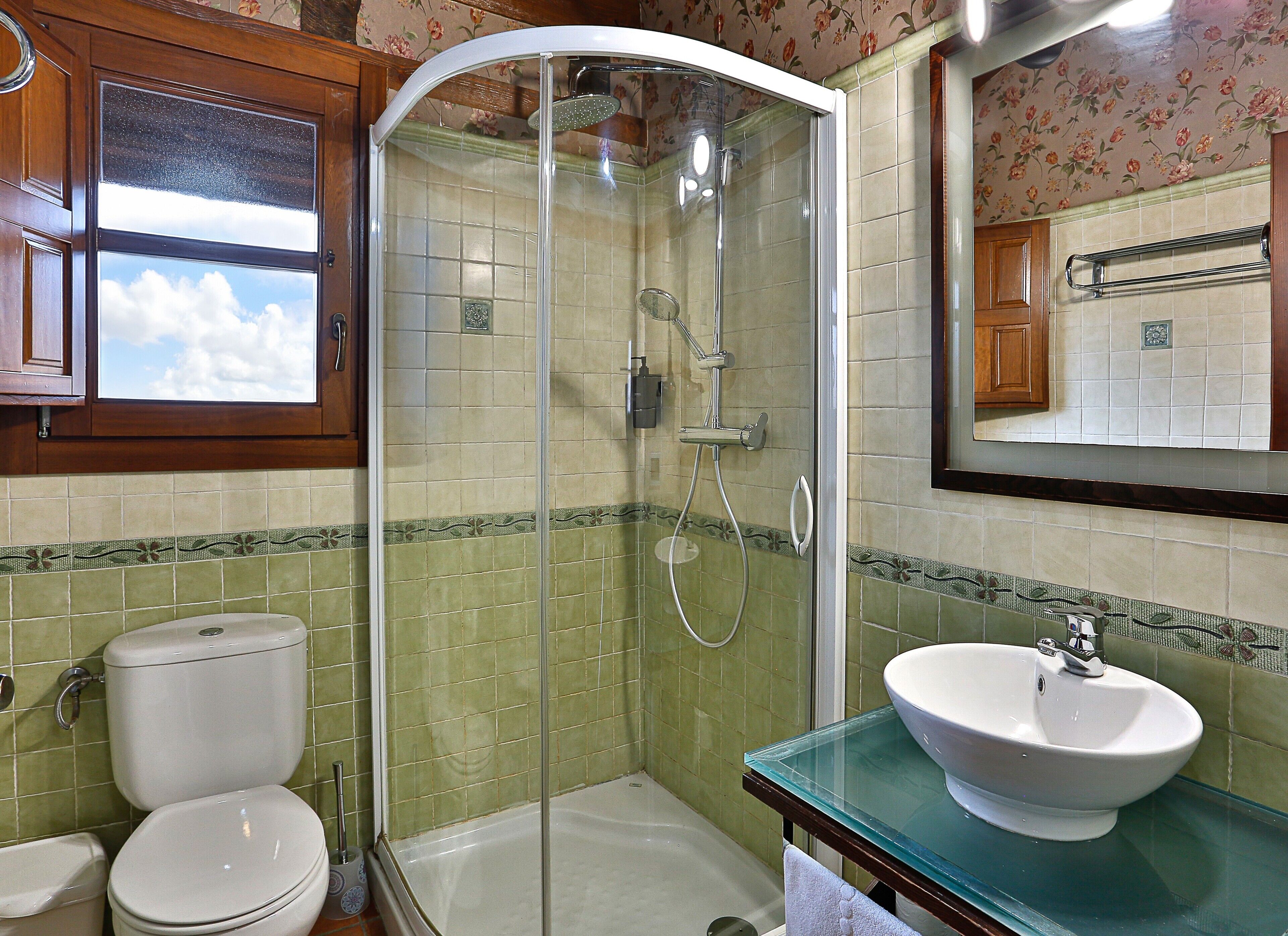 Een badkamer met een douchecabine van glas, een toilet en een wastafel met een glazen blad.