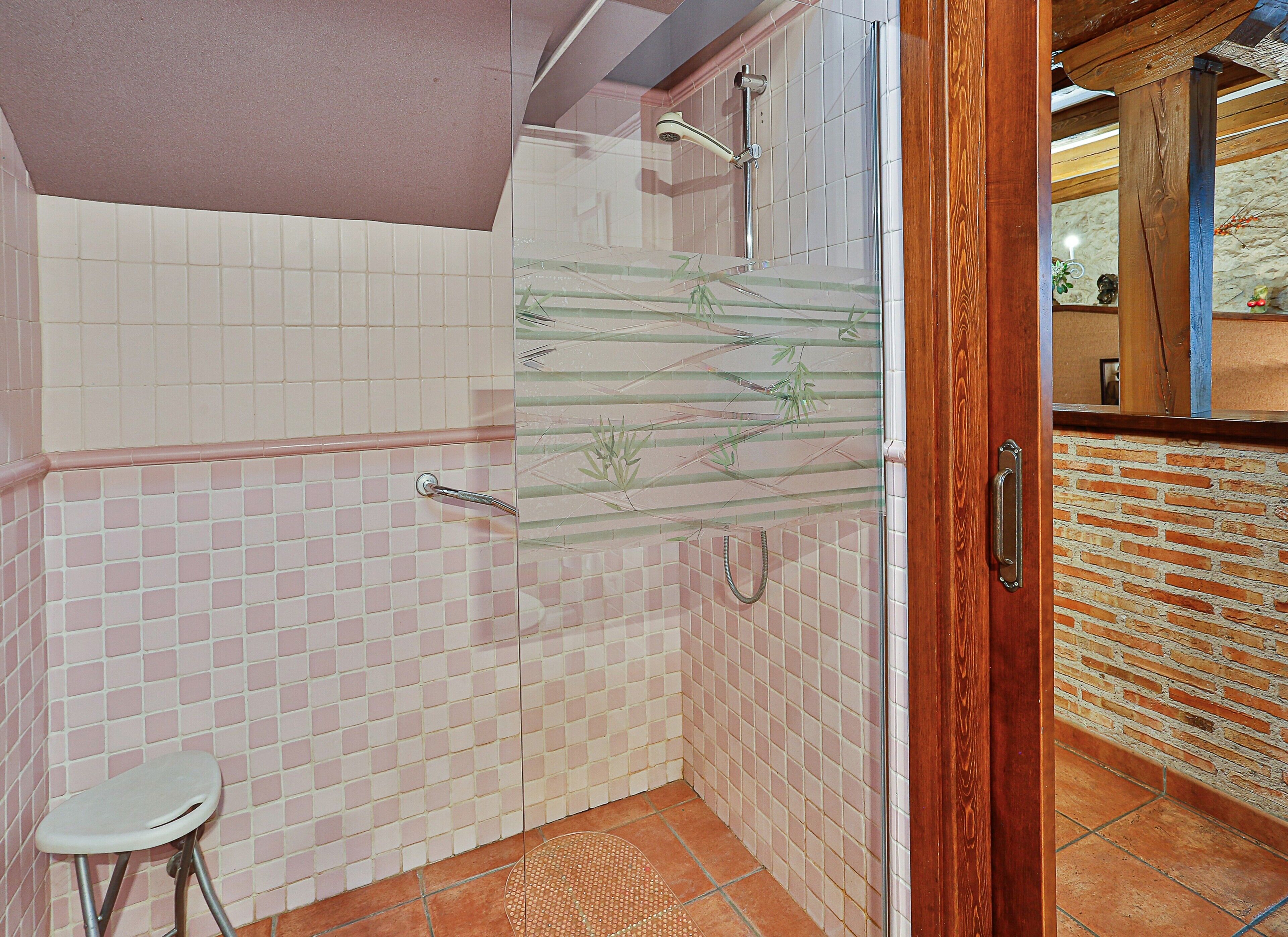 Een badkamer met een douche, toilet en een houten deur.