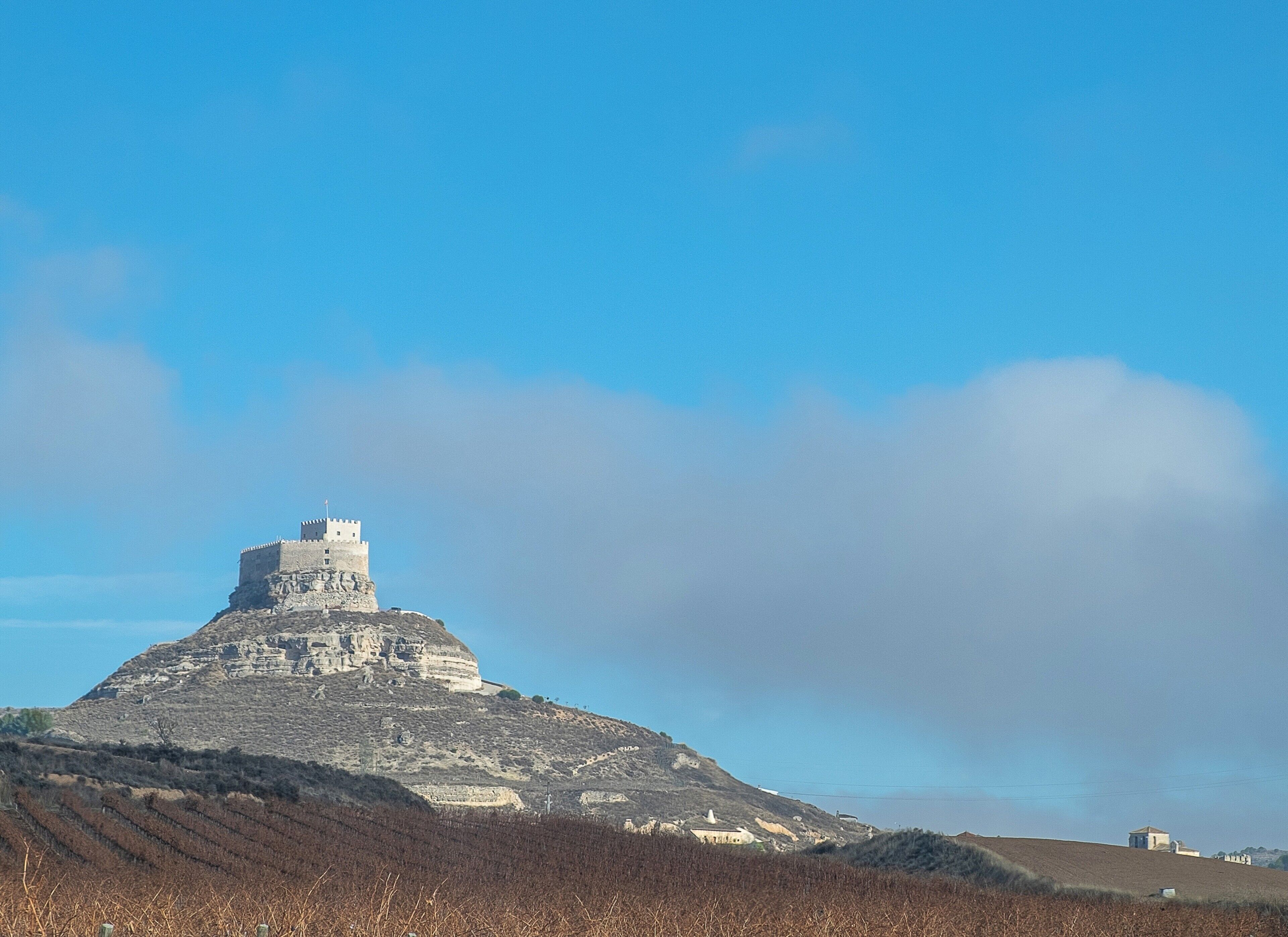 Un castell sobre un turó sota un cel serè.