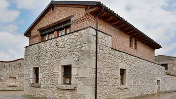 A stone building with a brick upper section, multiple windows, and a tiled roof.