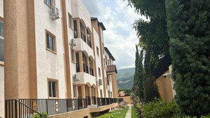 A multi-story building with balconies, a stone pathway, and lush greenery. - Charming 2-bedroom apartment with WiFi, AC in wonderful Kingston (Kingston)