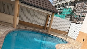 A swimming pool with a tiled edge and a metal ladder. - Charming 2-bedroom apartment with WiFi, AC in wonderful Kingston (Kingston)