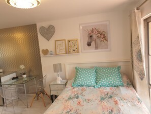 Relax in a stylish bedroom with a glass desk, comfortable bed, and beautiful artwork.