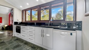 A modern kitchen with white cabinets, a black countertop, and a built-in dishwasher. - Wongalinga Beachfront Apt 5 (Wongaling Beach)