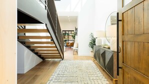 Un interior moderno con una escalera, piso de madera, un tapete blanco y un mueble de madera.